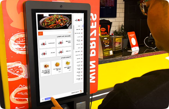 Customer using a Mealzo self-ordering kiosk to place a food order at a takeaway for faster service