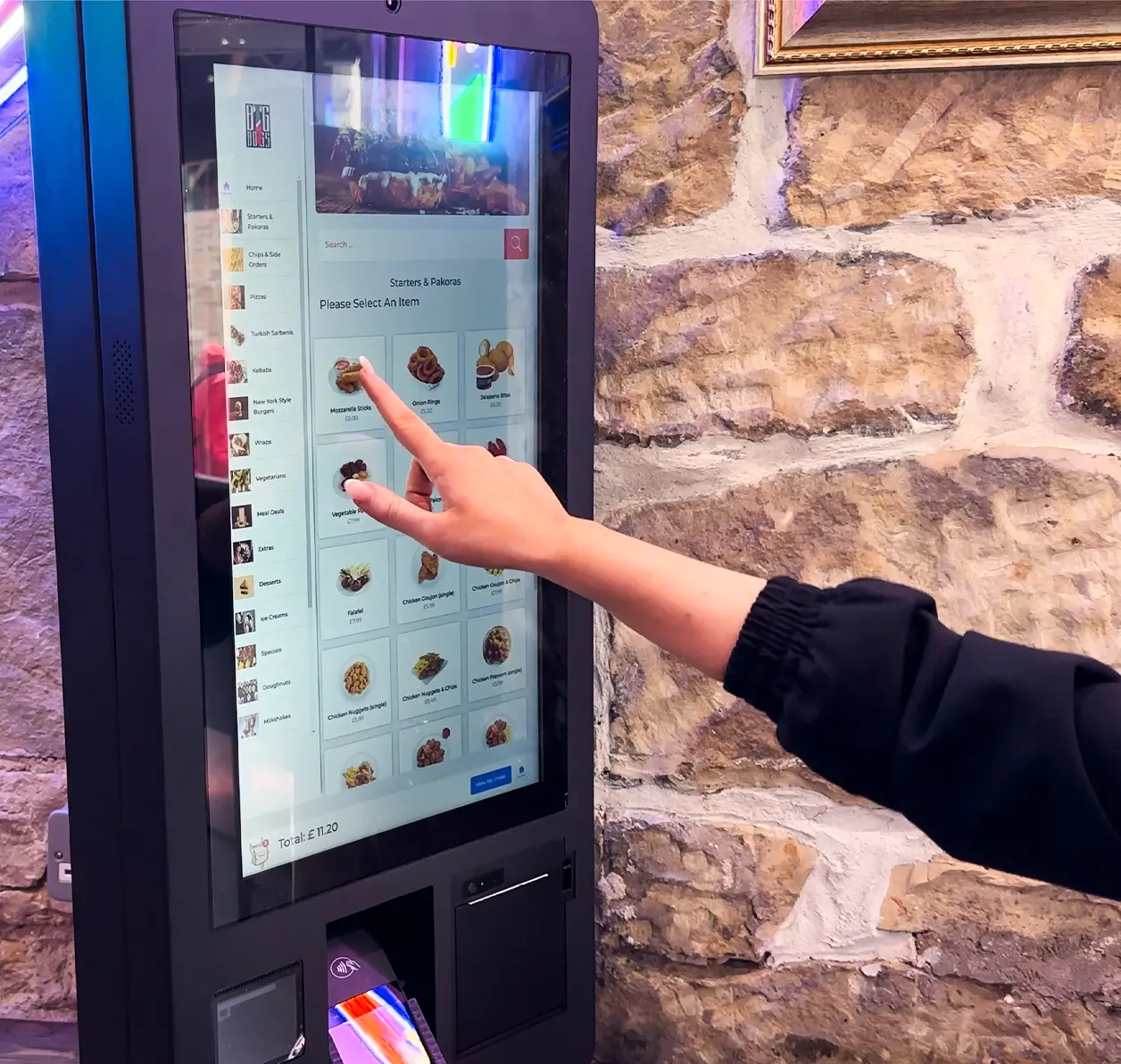 Customer using a Mealzo self-ordering kiosk to place a food order at a takeaway for faster service